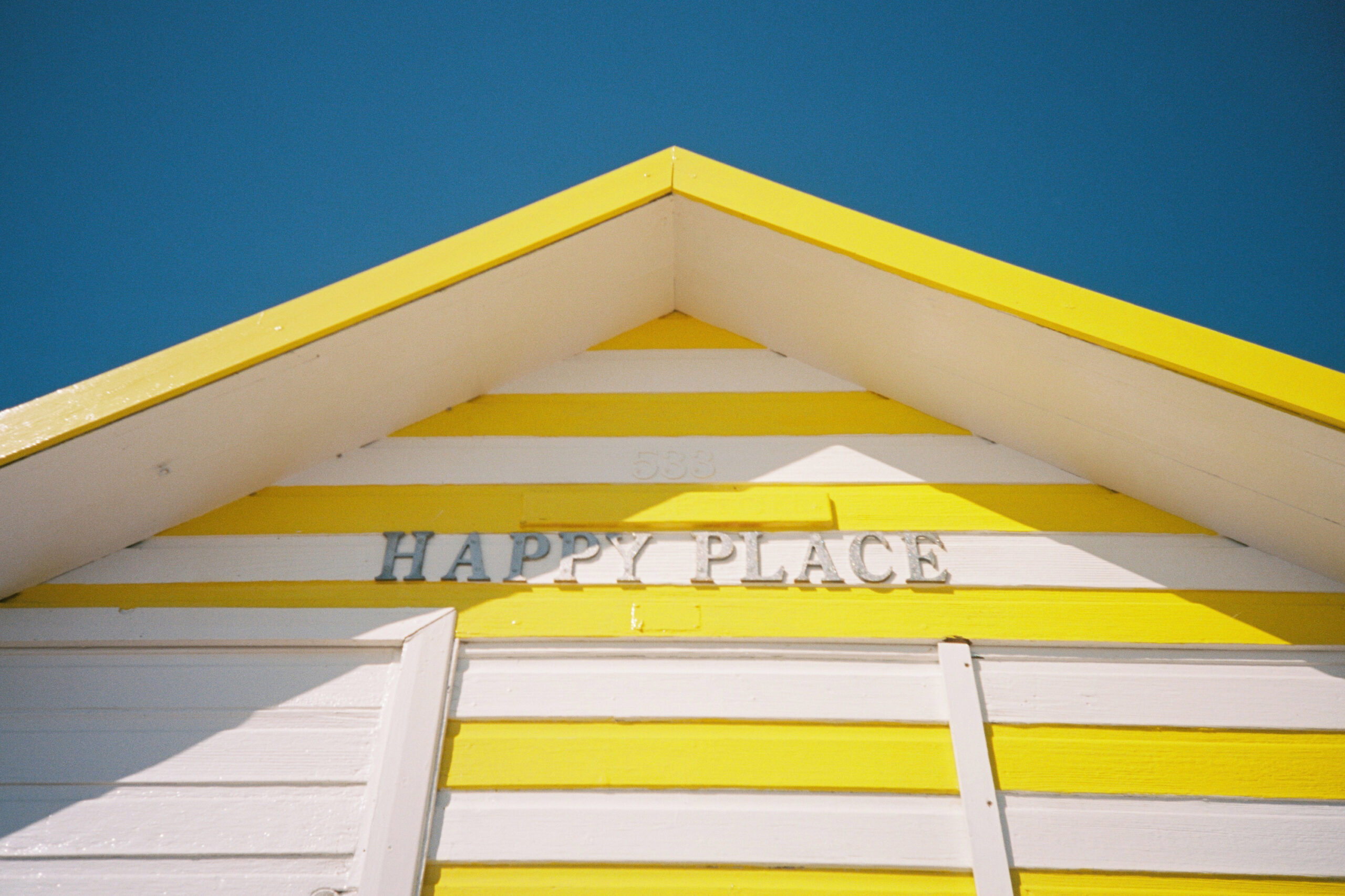 A colourful beach hut called "Happy Place".